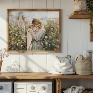 May include: A framed painting of a woman holding a baby in a field of flowers. The woman is wearing a blue dress and the baby is wearing a pink dress. The painting is set against a white wall with a wooden shelf above it.