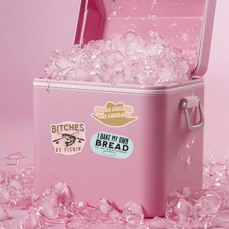 May include: A pink cooler with ice inside and three stickers on the side. The stickers say "Chase Sunsets Not Cowboys", "Bitches Be Fishin'" and "I Bake My Own Bread and I Don't Trust The Government".
