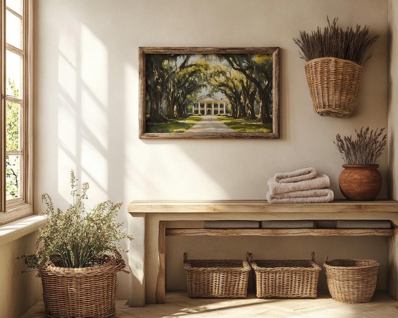 May include: A wooden bench with three woven baskets underneath. The bench is against a white wall with a framed painting of a house with trees above it. There are two dried flower arrangements in woven baskets on the wall.