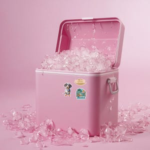 Puede incluir: Una nevera port&aacute;til de color rosa brillante con la tapa abierta, llena de cubitos de hielo transparentes. La parte frontal de la nevera tiene dos pegatinas: una que representa un perro salchicha y otra una escena de playa tropical con el texto Mexico.