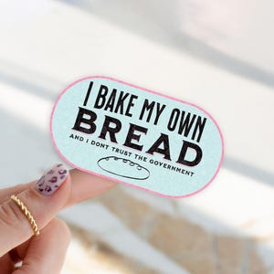 May include: A light blue and pink sticker with the text "I bake my own bread and I don't trust the government".