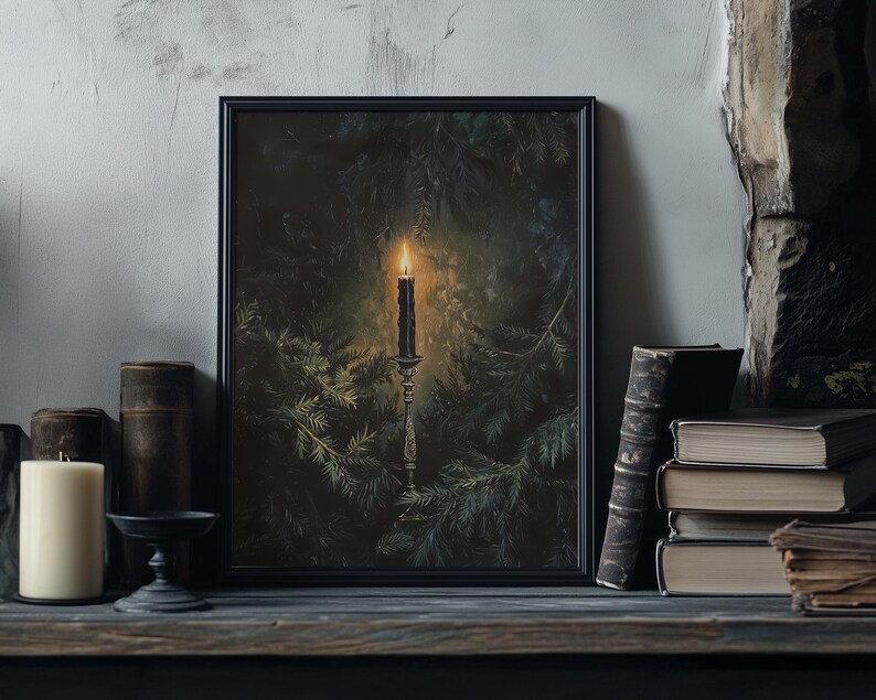 May include: A black framed print of a candle burning in a dark forest setting. The candle is on a silver candlestick and is surrounded by pine branches.