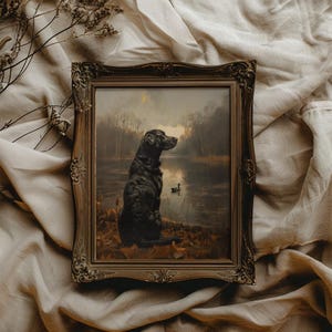 May include: A framed painting depicting a black Labrador Retriever seated by a lake, gazing out at the water. The dog is in the foreground, with the lake in the background. The painting is set in a rustic, woodland scene.