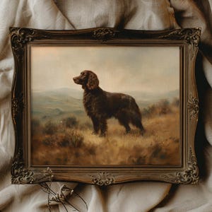 Peut inclure: Peinture encadrée ancienne d'un chien brun dans un champ. Le chien est au centre, sur fond de collines et de ciel doux. Le cadre orné, brun foncé, ajoute une touche vintage à l'ensemble.