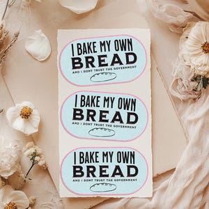 May include: Three stickers with a blue and pink background and black text that reads "I bake my own bread and I don't trust the government". Each sticker has a small illustration of a loaf of bread.