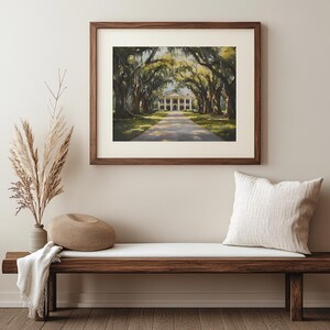 May include: A framed painting of a white building with columns, surrounded by a canopy of green trees. The building is at the end of a long, paved driveway.