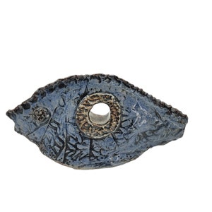 Op de afbeelding: Een blauwe keramische vissenbeeld met een getextureerd oppervlak en een gouden ring rond een gat in het midden.