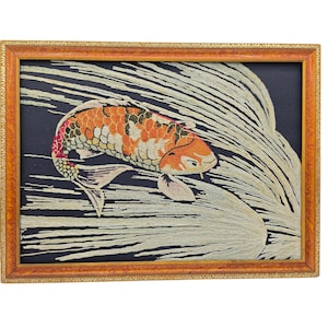 May include: A framed embroidery piece featuring a koi fish with orange, white, and black scales swimming through long, flowing white thread lines on a dark navy background. The artwork is enclosed in a rectangular, textured orange-brown frame.