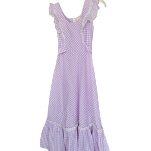 May include: A purple and white gingham dress with white lace trim on the neckline and sleeves. The dress has a ruffled hem.