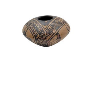 May include: A hand-painted, oval-shaped pottery vessel with a dark interior and a tan exterior. The exterior features intricate black and reddish-brown geometric patterns and floral motifs. The vessel has a smooth, polished finish.