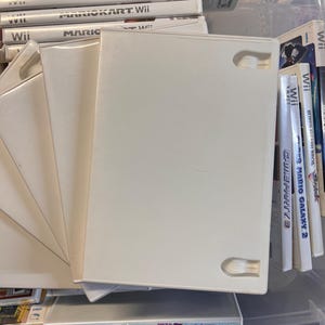 May include: A collection of white Wii game cases, some empty, others containing game discs. The cases are stacked and fanned out, with the game titles visible on the spines. The games include Mario Kart Wii and Super Mario Galaxy 2.