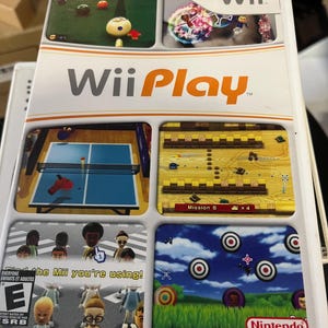 May include: Wii Play video game case. The cover features the game's title in orange and white, with multiple game scenes displayed in boxes. The game scenes include bowling, table tennis, and target shooting. The ESRB rating is visible.