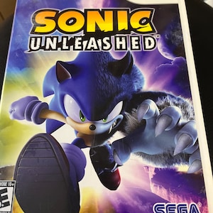 May include: A Wii game case for "Sonic Unleashed" featuring Sonic the Hedgehog in a blue and gray werewolf form. The game title is in yellow and white, with the Sega logo at the bottom.