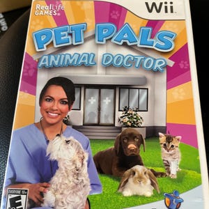 May include: Wii game case for "Pet Pals Animal Doctor." The cover features a smiling woman in scrubs holding a small white dog. Other animals include a brown dog, a kitten, and a rabbit. The game is rated "Everyone 10+".