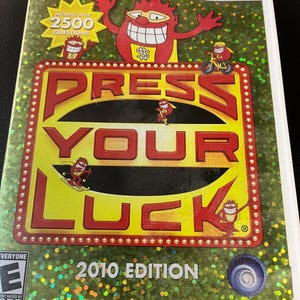 May include: A Wii game case for "Press Your Luck: 2010 Edition." The cover features a red cartoon character with a large grin and dollar sign on its chest. The game's title is in large red letters on a yellow background.