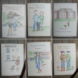 May include: A collection of six hand-drawn greeting cards. The cards feature illustrations of houses, couples, and families, with text such as "Wishing you happiness," "Coming Soon," "Happy Birthday," and "Merry Christmas." The cards are on a wooden surface.