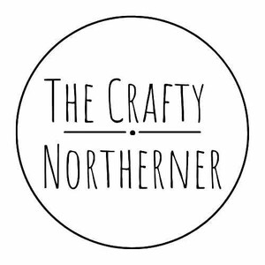 May include: A black and white logo within a circle. The text reads "THE CRAFTY NORTHERNER" in a handwritten style font. The words are separated by a horizontal line and a dot.