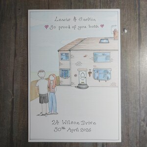 May include: A hand-drawn illustration of a house with a couple standing in front. The text reads "Lewis & Saskia, So proud of you both" with a heart symbol. The address "24 Wilson Drive" and the date "30th April 2026" are also included.