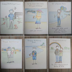 May include: A collection of six hand-drawn greeting cards with various celebratory messages. The cards feature illustrations of people, beach scenes, and text such as "Happy Birthday" and "Congratulations". The cards are on a wooden surface.