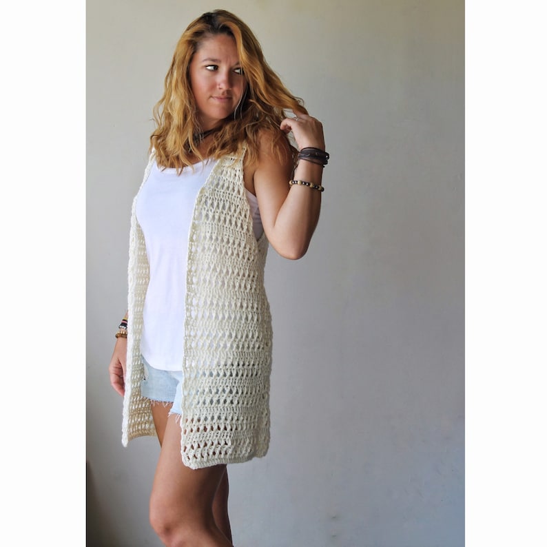 May include: A white crochet vest with a loose, open-weave design. The vest is sleeveless and has a long, flowing silhouette.