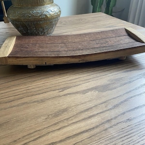 May include: A curved wooden serving tray made from reclaimed barrel staves. The tray features a dark brown center with lighter wood accents on the ends. The tray is approximately 18 inches long and 6 inches wide.