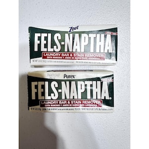 Può includere: Due saponette Fels-Naptha per bucato e smacchiatore. Le saponette hanno un'etichetta bianca, verde e nera. Il testo sull'etichetta include "FELS-NAPTHA", "LAUNDRY BAR & STAIN REMOVER" e "SINCE 1894".