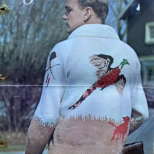 Peut inclure: Couverture d'un patron de tricot vintage avec un homme portant un pull blanc orné d'un motif de faisan rouge, noir et vert. Le texte "Mary Maxim" et "No. 1813" sont visibles.