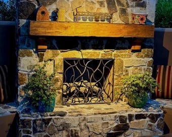 May include: A stone fireplace with a wrought iron screen and a wooden mantel. The fireplace is decorated with potted plants and a small birdhouse.