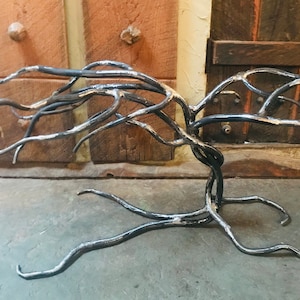 May include: A black metal tree sculpture with a unique, twisted branch design. The sculpture is made of metal and has a rustic, industrial look.