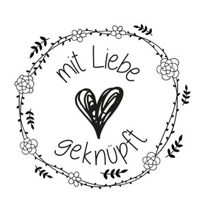 May include: Black and white illustration of a wreath with flowers and leaves. The wreath has the text "mit Liebe gekn&uuml;pft" in the center.