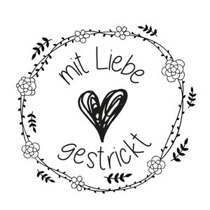 May include: Black and white illustration of a wreath with flowers and leaves. The wreath has the text "mit Liebe gestrickt" in the center.
