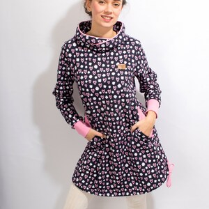 Puede incluir: Un vestido azul marino con un estampado de corazones rosas y blancos. El vestido tiene cuello alto, mangas largas y dos bolsillos. El vestido est&aacute; hecho de una tela suave y c&oacute;moda.