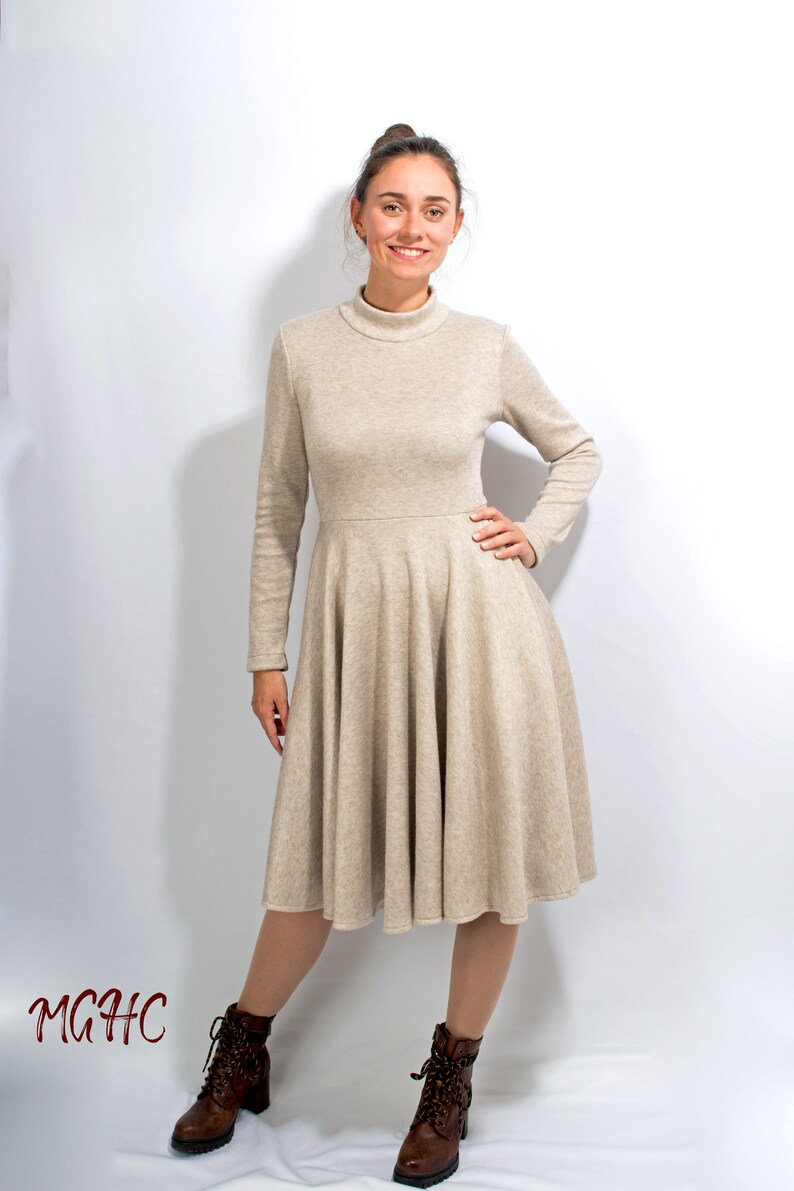 May include: A beige long-sleeved dress with a high neck and a flared skirt. The dress is made of a soft, comfortable fabric and is perfect for a casual or semi-formal occasion.