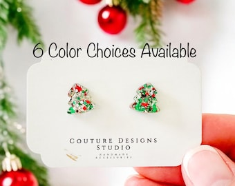 May include: A pair of Christmas tree earrings with red, green, and silver glitter. The earrings are on a white card with the text "6 Color Choices Available" and "Couture Designs Studio Handmade Accessories".