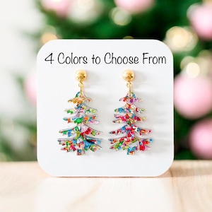 May include: A pair of Christmas tree earrings with gold-colored posts. The earrings are shaped like Christmas trees and are decorated with colorful confetti-like patterns. The image also includes the text "4 Colors to Choose From".