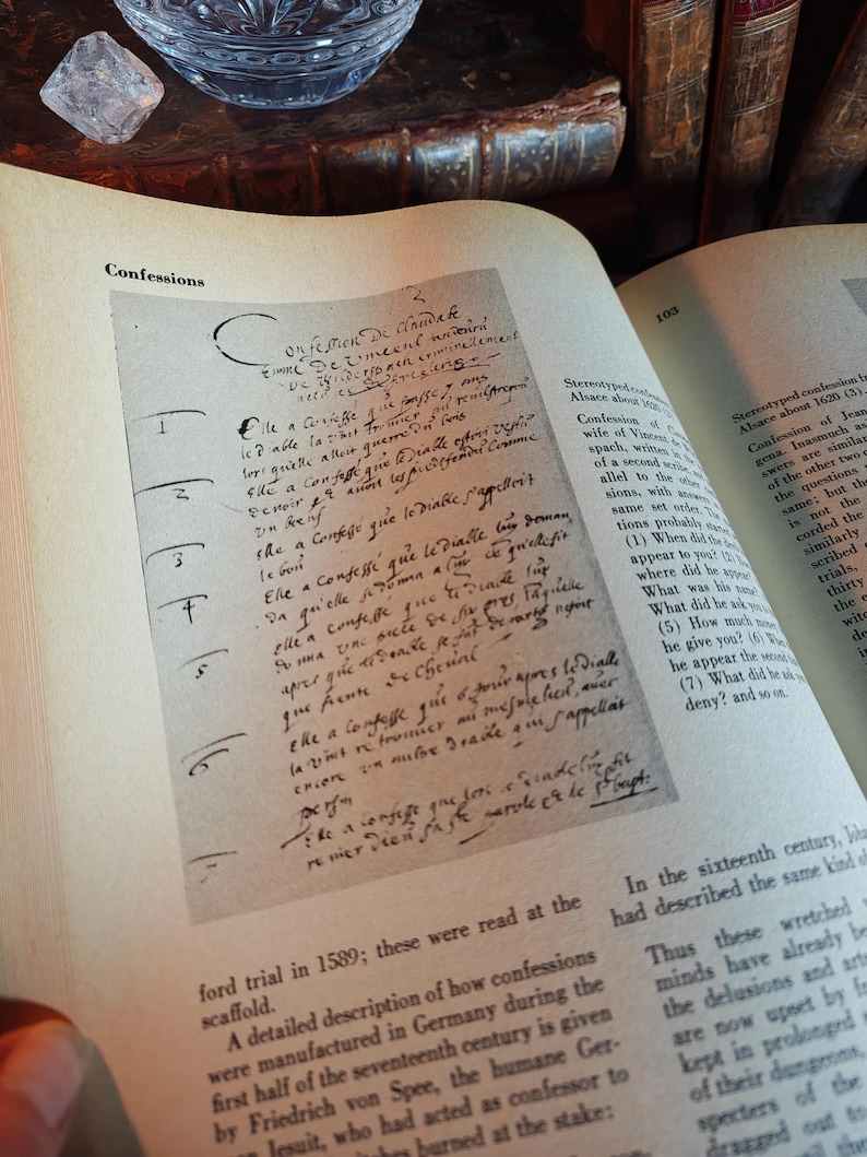 May include: An open book with text and handwritten notes. The page shows the word "Confessions" at the top. The text is in a script font. The book is open to a page with a detailed description of confessions.