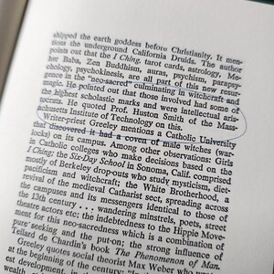 May include: Open book page with printed text. A blue circle highlights the text "Catholic University". The text discusses topics like witchcraft, mysticism, and the I Ching, with references to various authors and institutions.
