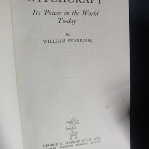 Może przedstawiać: Otwarta książka zatytułowana "WITCHCRAFT" autorstwa Williama Seabrooka. Tytuł jest pogrubiony, z podtytułem "Its Power in the World To-day" poniżej. Nazwisko autora jest wyśrodkowane. Logo i nazwa wydawcy znajdują się na dole.