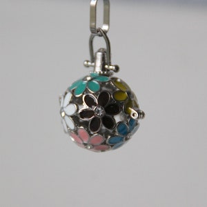Könnte beinhalten: Eine silberne Anhänger-Kette mit einem runden Anhänger, der mit einem Design aus bunten Blumen verziert ist. Der Anhänger ist aus Metall und hat eine glänzende Oberfläche.