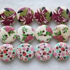 May include: Twelve wooden buttons with floral and geometric designs. The buttons are in shades of pink, green, white, and black.
