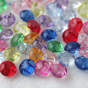 Peut inclure: Assortiment de boutons en plastique colorés avec un motif en croisillons. Les boutons sont de différentes couleurs, notamment rouge, bleu, vert, jaune, rose et transparent.