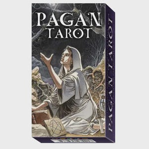 Puede incluir: Una caja rectangular de cartas de tarot Pagan que muestra una figura encapuchada con túnica blanca extendiendo las manos hacia arriba en un entorno boscoso oscuro. La caja presenta el texto PAGAN TAROT en letras blancas en la parte superior y lateral.