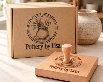Puede incluir: Una caja de cartón marrón y un sello de madera cuadrado, ambos con el logotipo de Pottery by Lisa, que muestra una planta en maceta y herramientas de alfarería en un marco circular. A la derecha hay un jarrón de cerámica moteado.