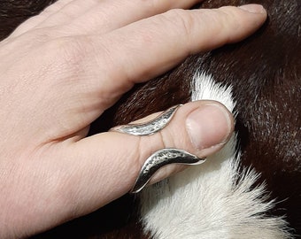 May include: A silver thumb ring with a hammered finish. The ring is open on one side and has a curved shape.