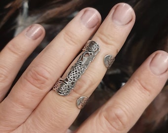 May include: A silver filigree ring with a delicate design. The ring is open on one side and can be adjusted to fit different finger sizes.