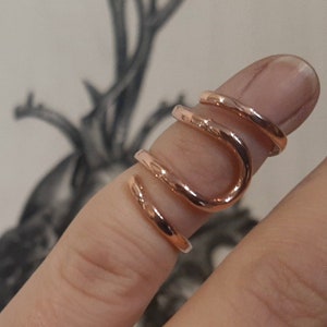 Puede incluir: Un anillo de oro rosa con un diseño único y retorcido. El anillo está hecho de múltiples bandas que se entrelazan para crear un efecto de espiral.
