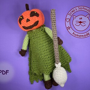 Könnte beinhalten: Häkelanleitung für eine Kürbishexe mit Besen. Die Hexe trägt ein grünes Kleid und hat einen braunen Kürbis-Kopf mit einem freundlichen Gesicht. Die Anleitung ist als PDF-Download erhältlich. "Drea's Saihoubako Homemade" steht auf einem roten Kreis mit einer Katze darin.