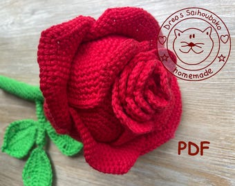 Op de afbeelding: Een handgemaakte, gehaakte rode roos met groene stengel en bladeren. De roos staat in volle bloei, met gedetailleerd bloemblaadjeswerk. De afbeelding bevat de tekst "PDF" en een cirkelvormig logo met de tekst "Drea's Saihoubako homemade".