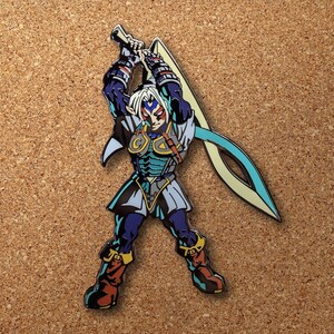 Op de afbeelding: Een blauwe en gouden emaille pin met een personage uit de Legend of Zelda-videogameserie. Het personage houdt een zwaard vast en heeft een blauw en wit masker.