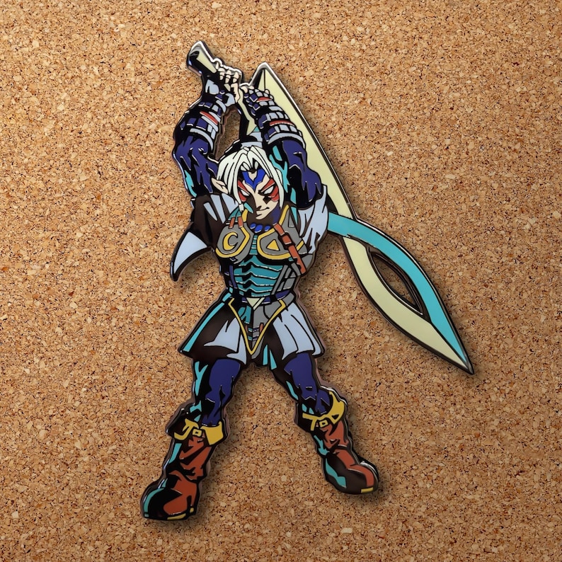 Op de afbeelding: Een blauwe en gouden emaille pin met een personage uit de Legend of Zelda-videogameserie. Het personage houdt een zwaard vast en heeft een blauw en wit masker.